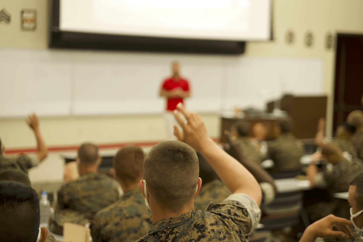 A group of soldiers are raising their hands to answer a question