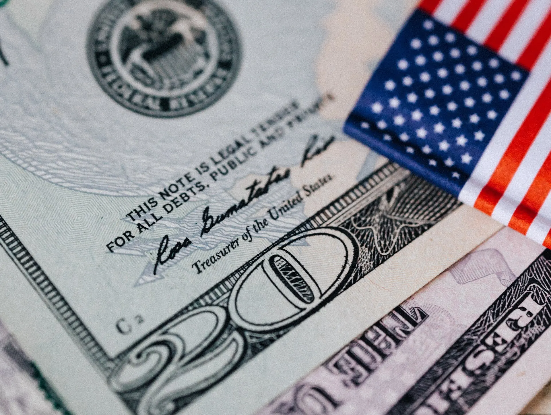 A close up of a 20 dollar bill next to an american flag