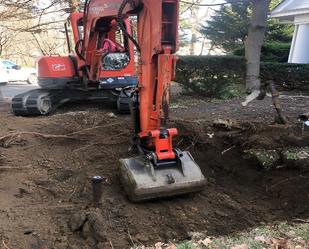 Orange excavator digging in a dirt area near a road and house. Orange excavator digging in a dirt area near a road and house.