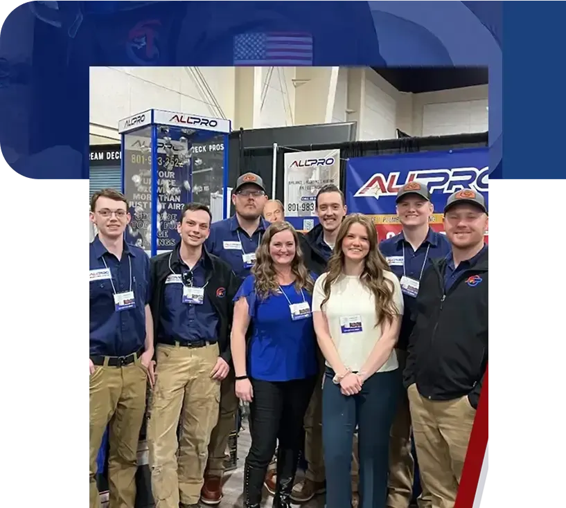 Man in uniform by AC unit, and company trucks; red and blue colors.