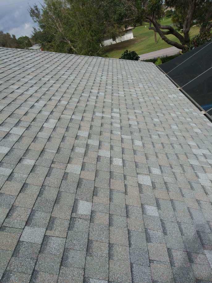 Gray asphalt shingle roof, some shingles missing, daytime exterior view.