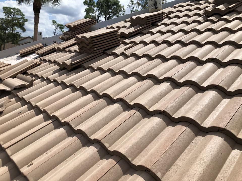Beige tile roof with stacks of tiles; clear sky in the background.