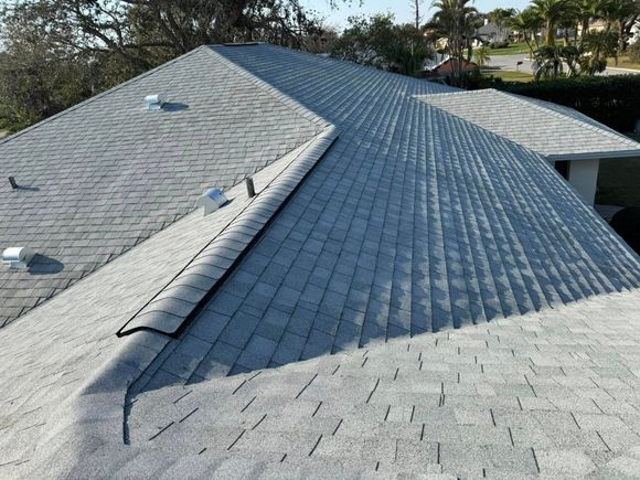 Gray shingle roof with multiple sections; a sunny outdoor setting.