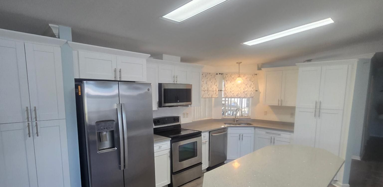 Modern white kitchen with stainless steel appliances, white cabinets, and a large island.