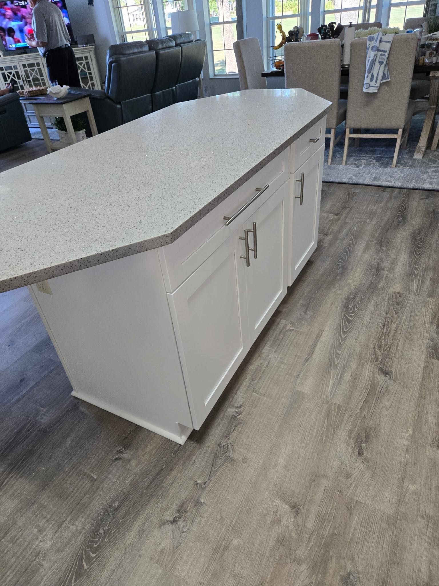 White kitchen island with gray speckled countertop; hardwood floors.