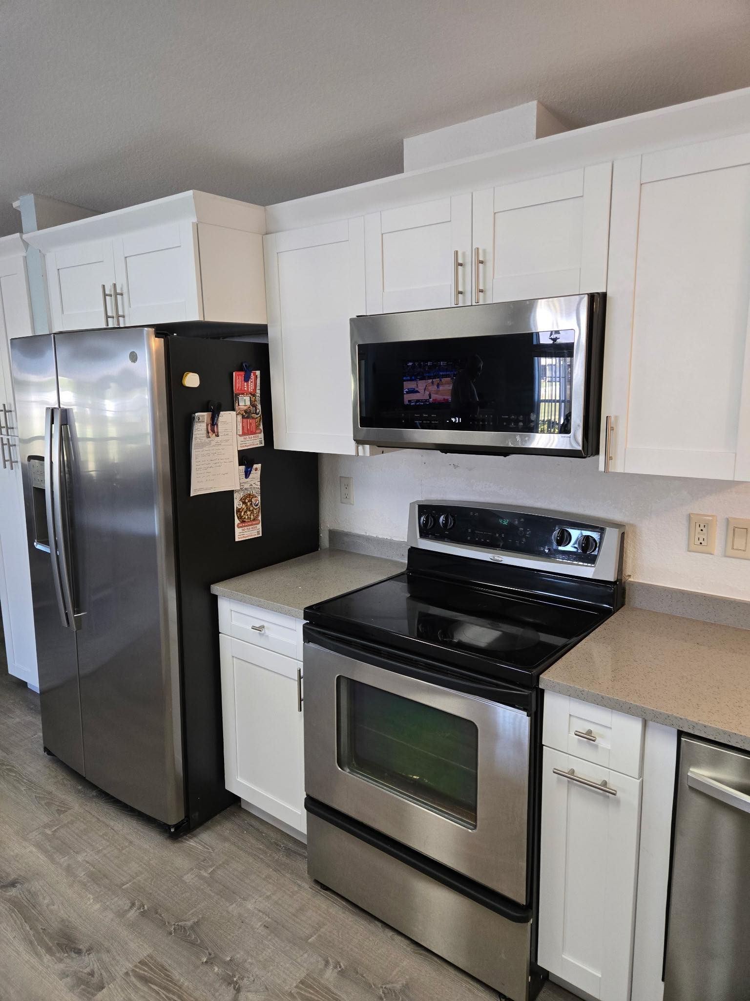 Stainless steel appliances in a white kitchen, including refrigerator, stove, microwave, and dishwasher.