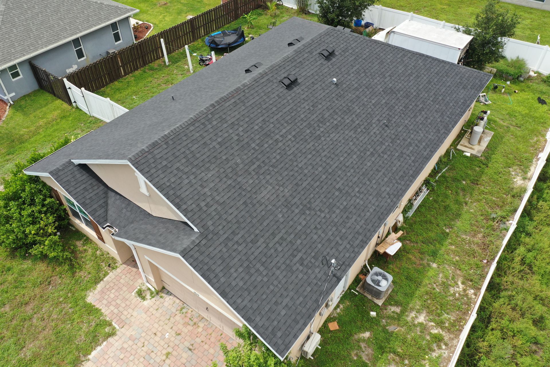 Aerial view of a house with a dark gray shingled roof in a grassy yard.