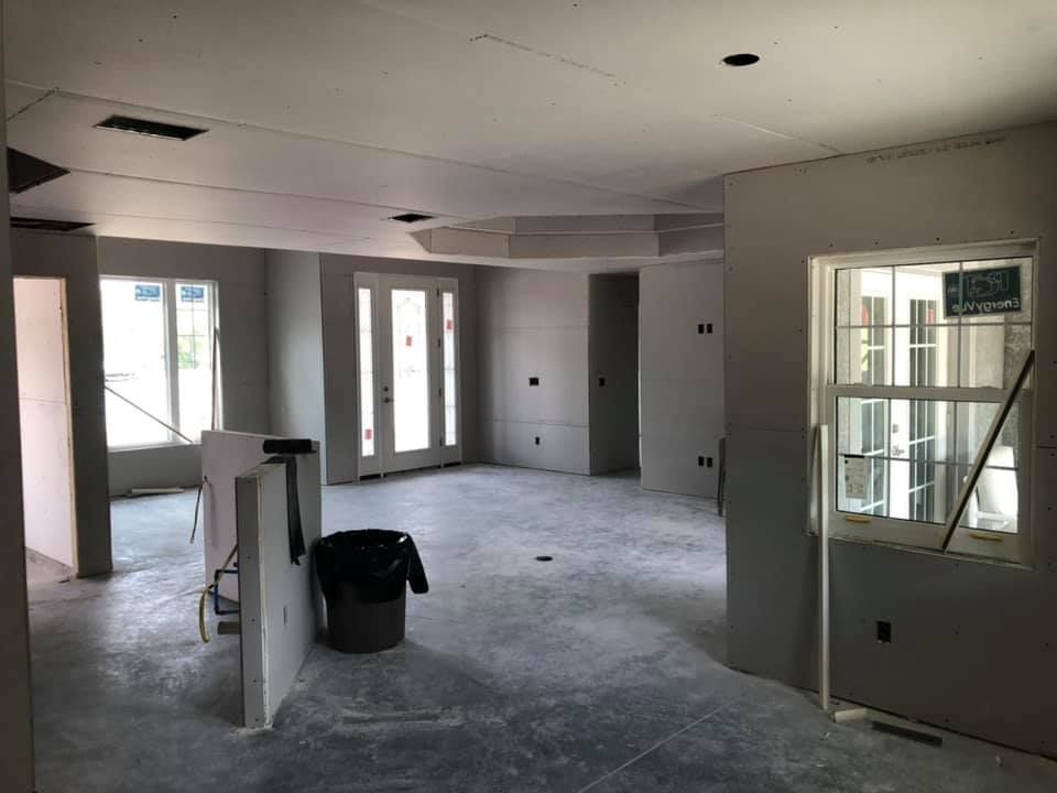Interior view of a room under construction; gray walls and floors, unfinished drywall.