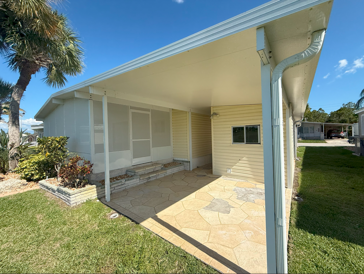 A single-story house with a covered porch, light-yellow siding, and a sunny outdoor setting.