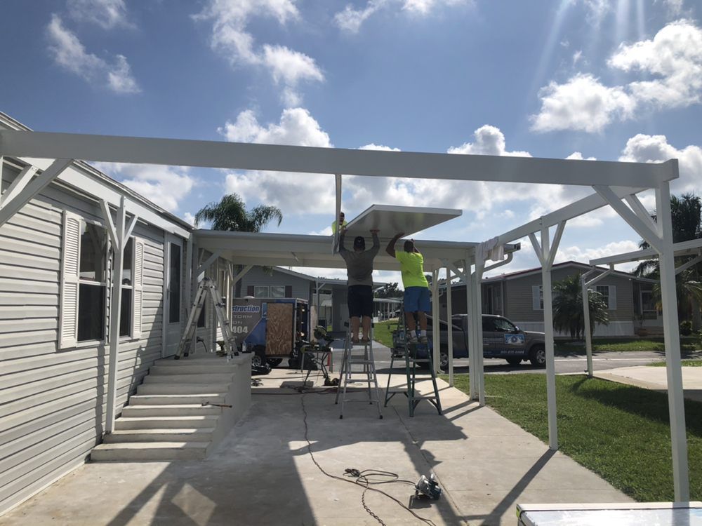 Workers installing a white pergola on a patio under a sunny sky.