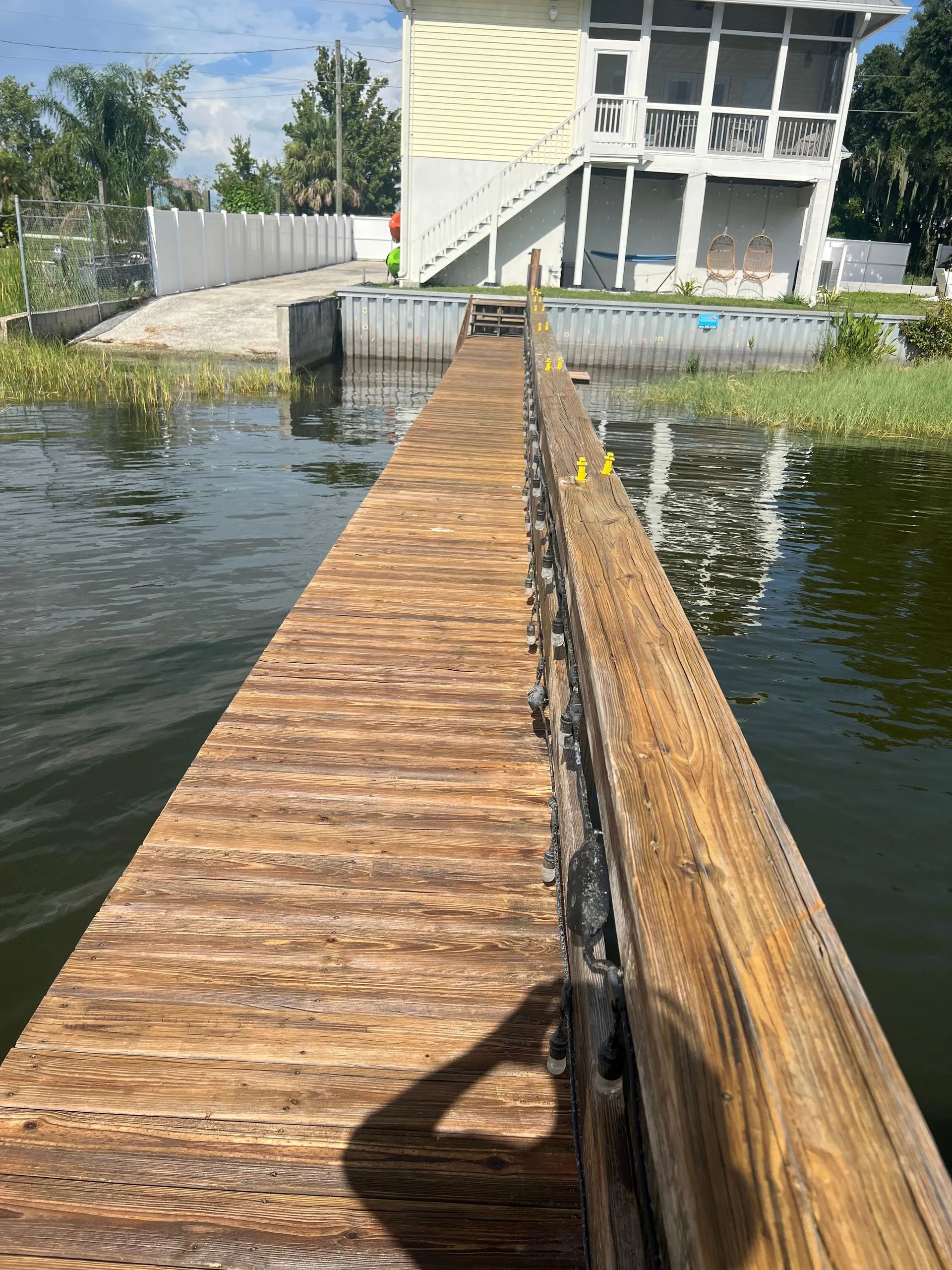 A wooden dock leading to a house on a lake.