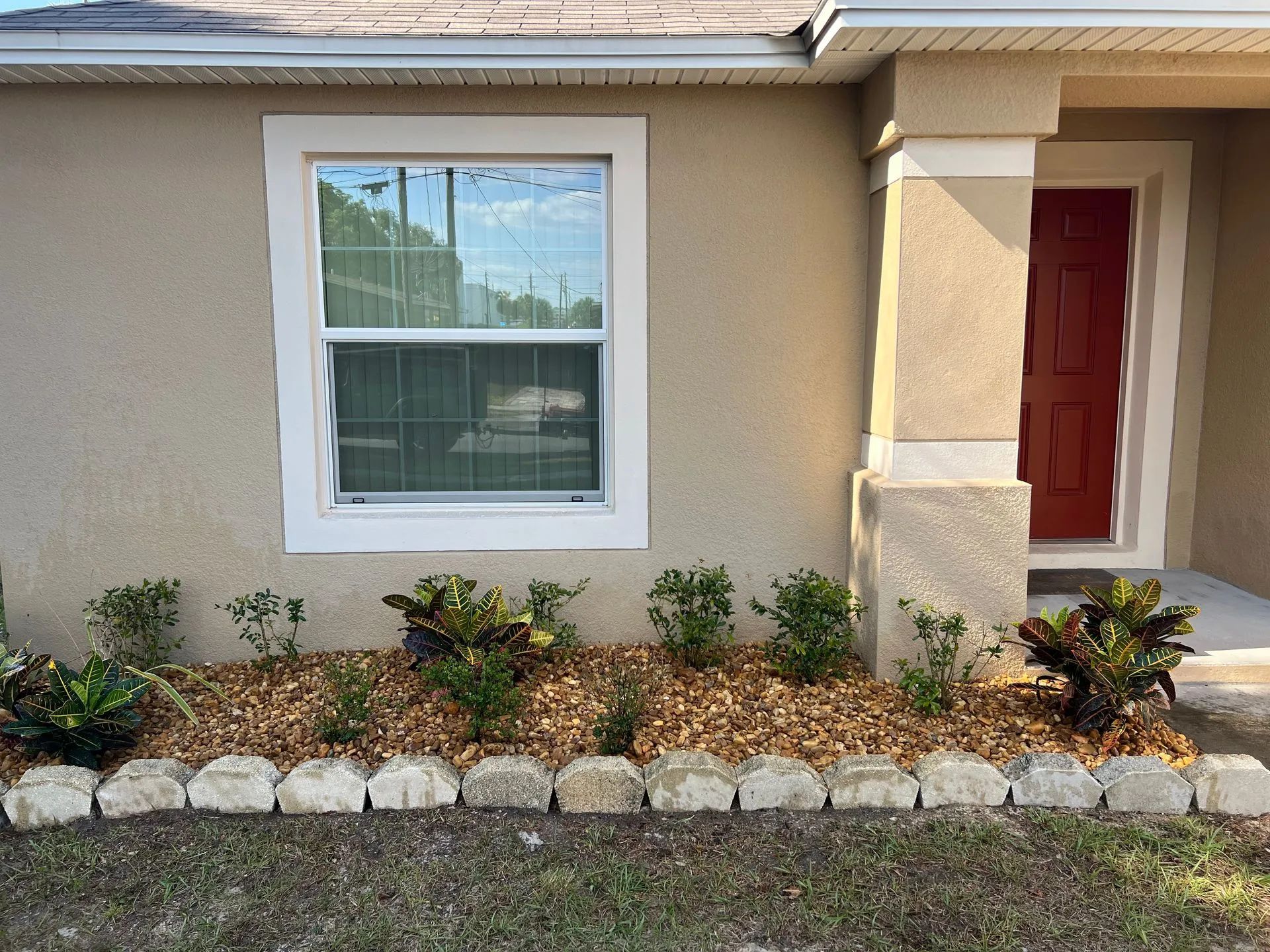 The front of a house with a window and a red door.