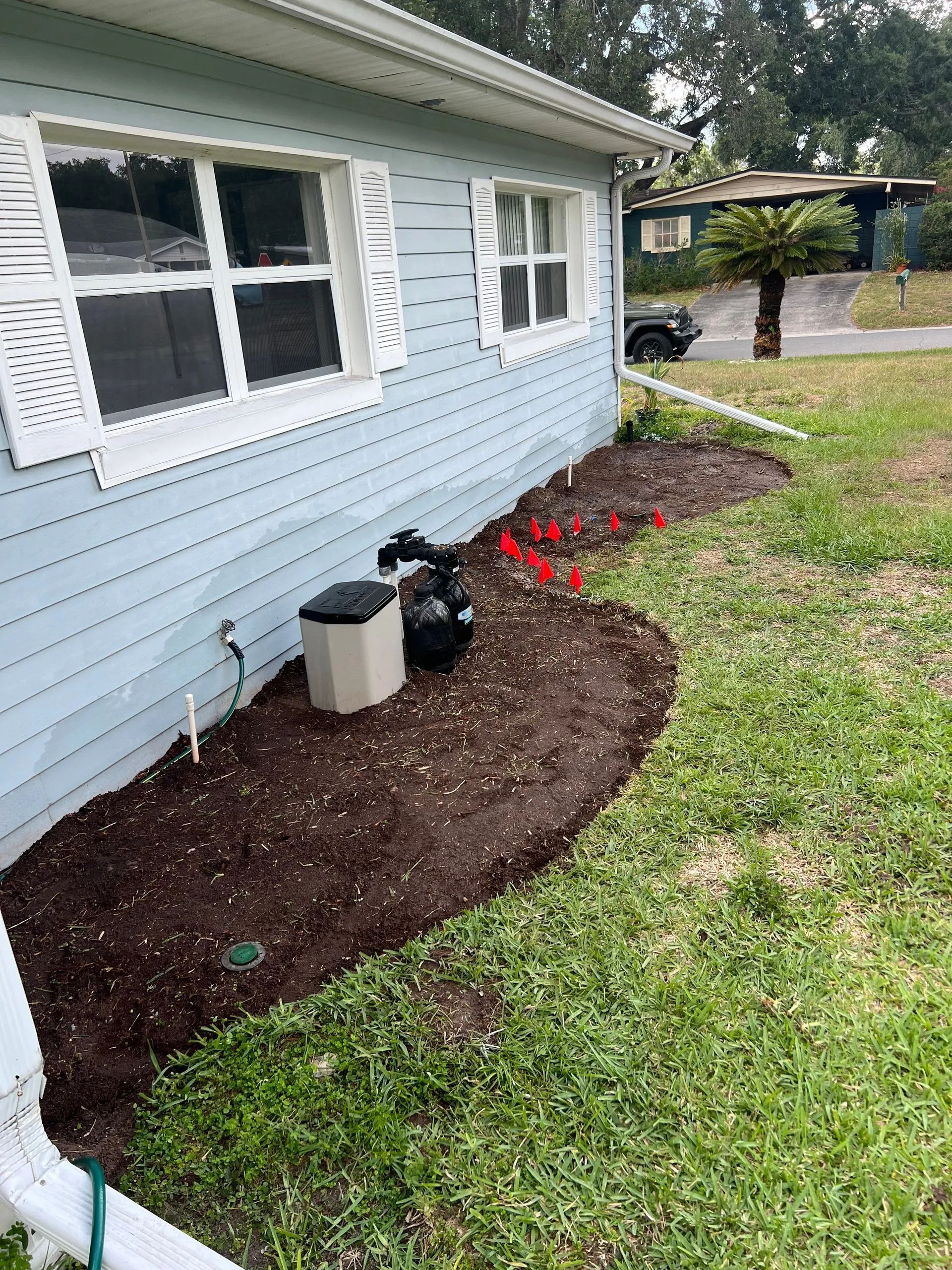 A blue house with a lawn and flowers in front of it.