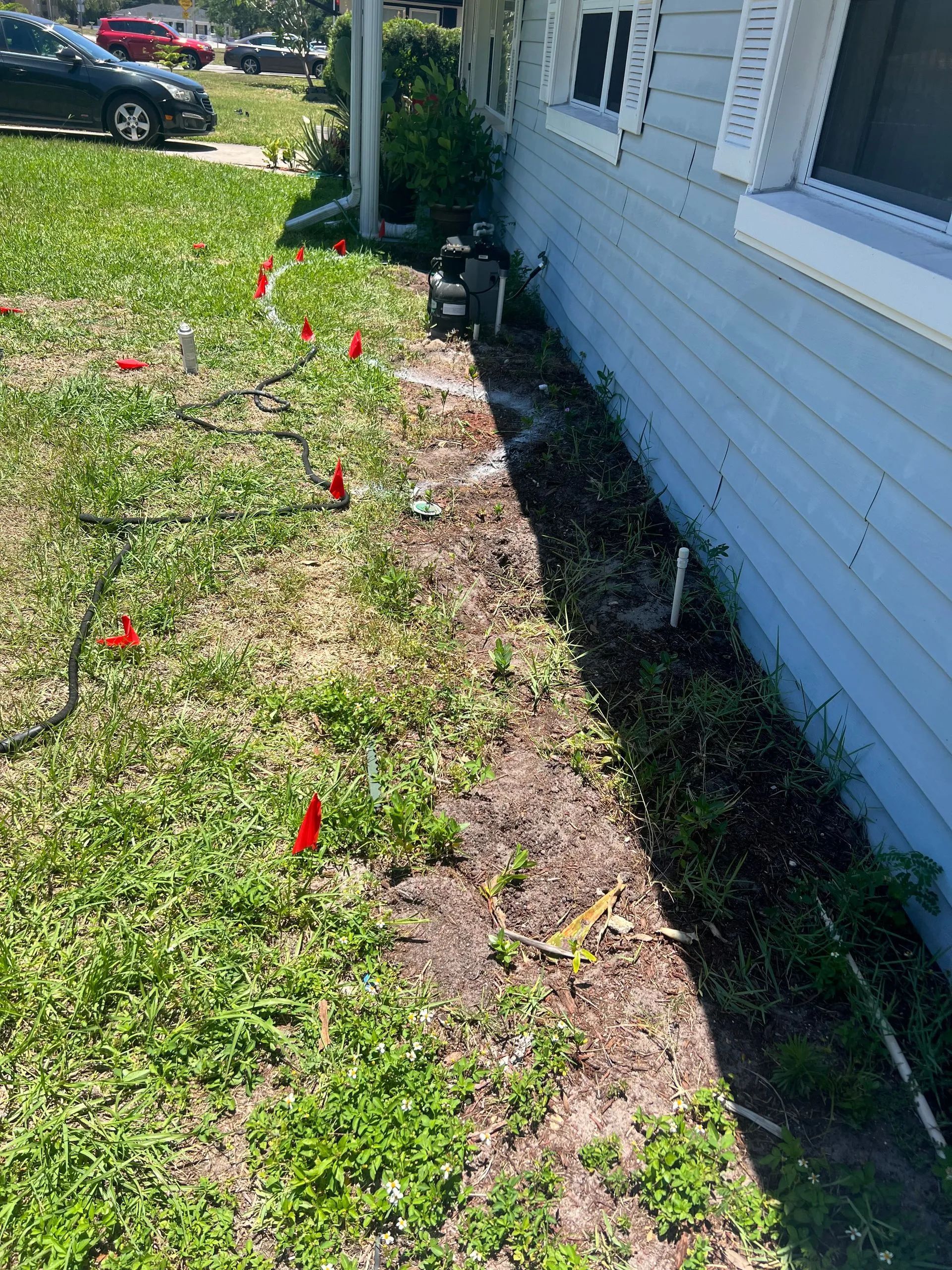 A house with a lot of grass and red flags in front of it.