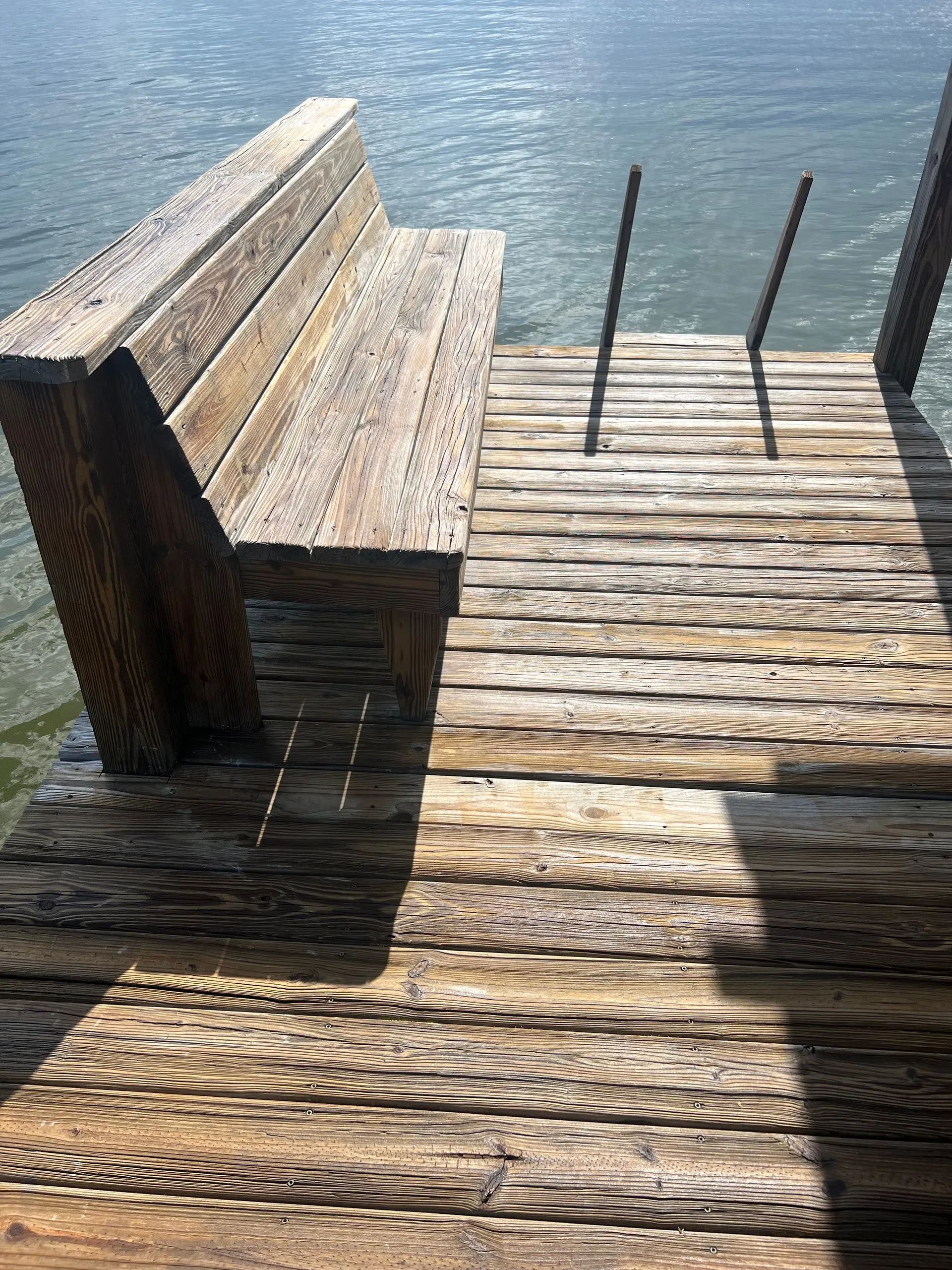 A wooden dock with a bench and stairs leading to the water.