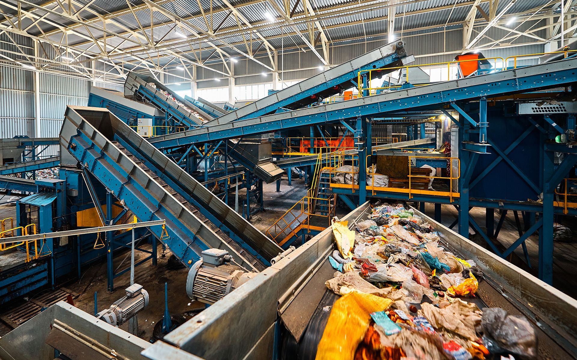 Inside a recycling plant, machinery sorts trash on conveyor belts.