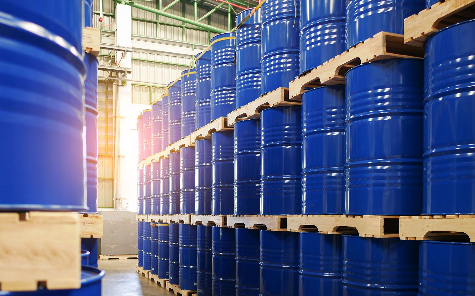 Rows of blue barrels stacked on wooden pallets inside a warehouse.