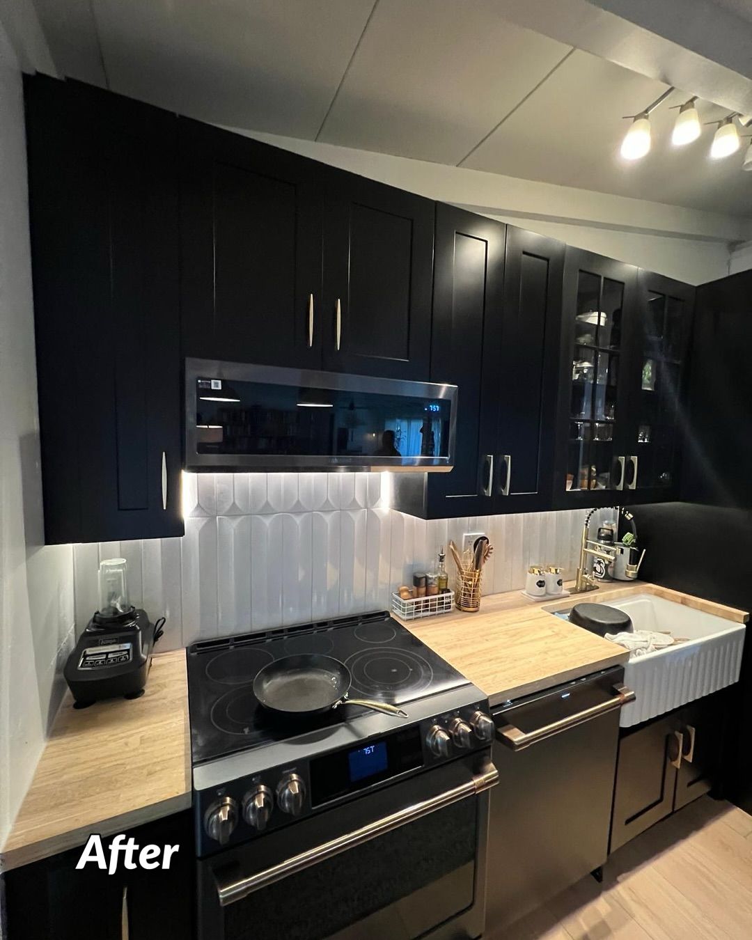 Modern black kitchen with white tile backsplash, wooden countertops, and stainless steel appliances.