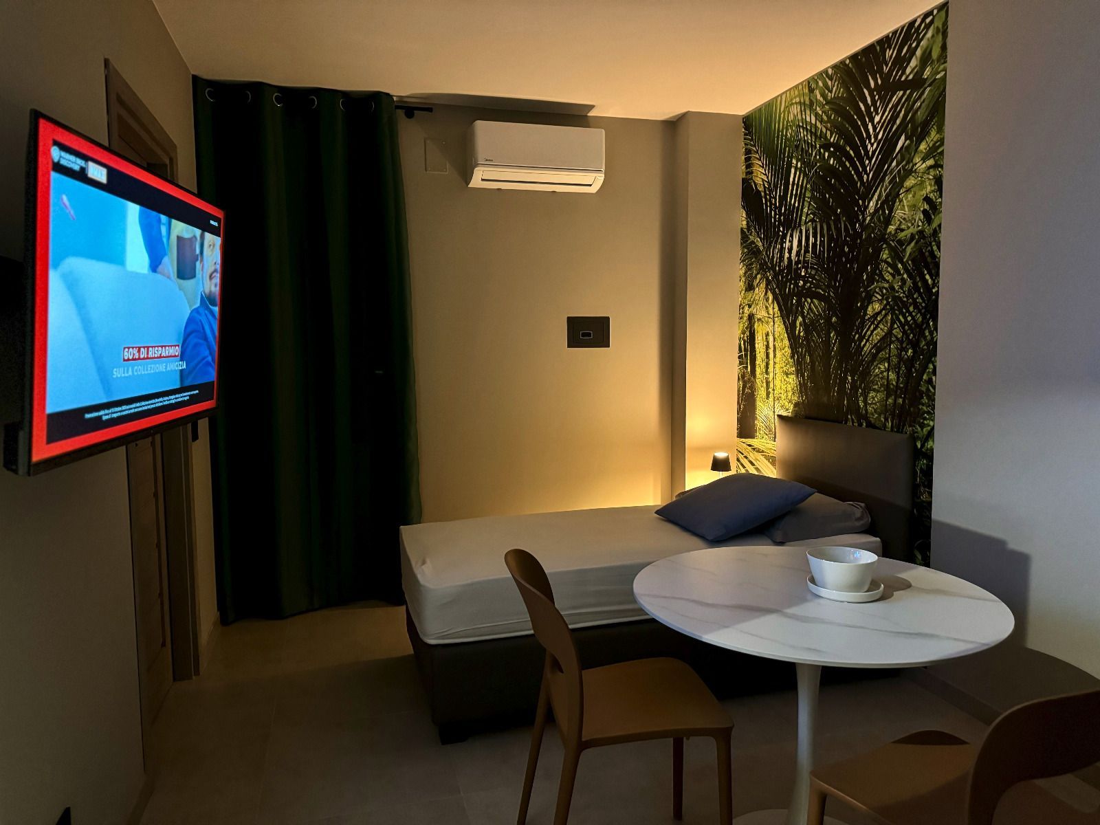 una piccola stanza con un letto e un tavolo e un televisore che mostra l' agenzia delle entrate