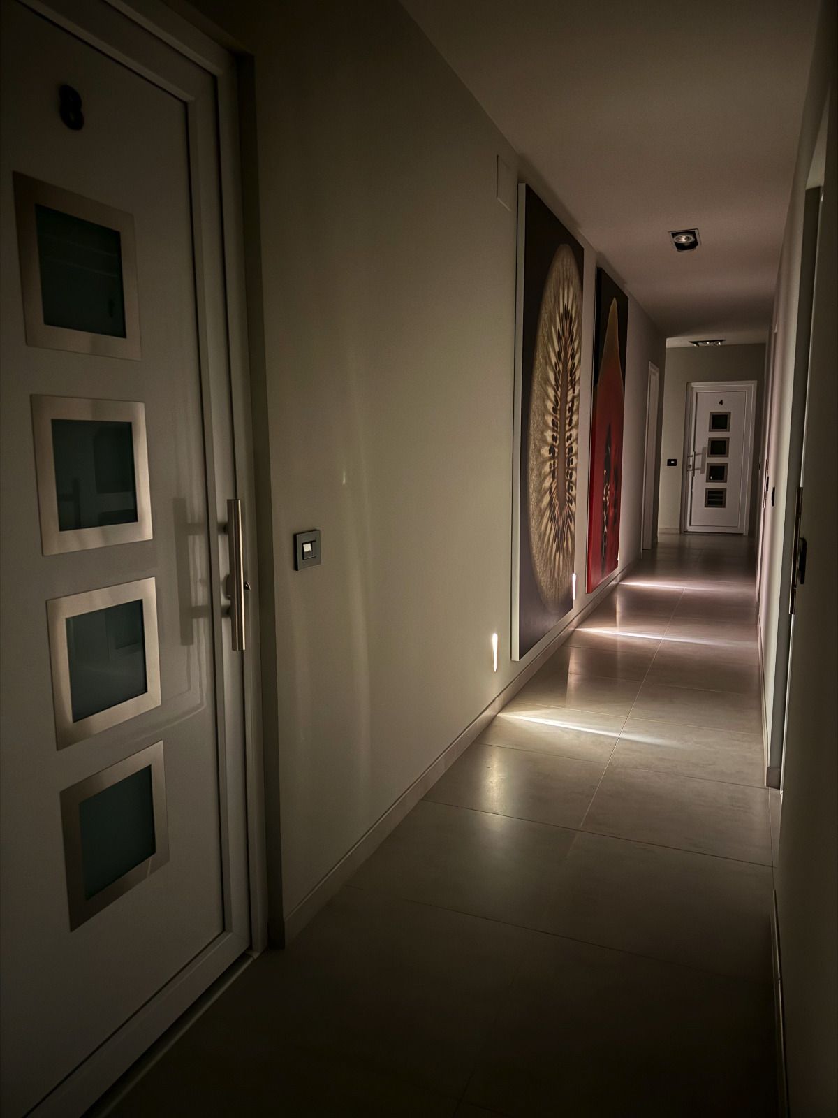 un corridoio buio con una porta bianca e quattro finestre