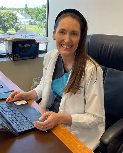 A smiling doctor in a lab coat with a stethoscope around his neck.