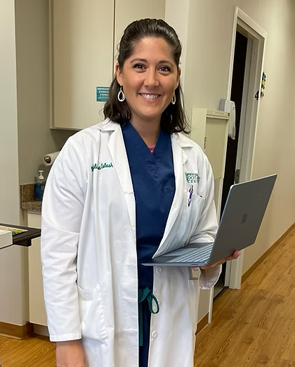 A smiling doctor in a lab coat with a stethoscope around his neck.