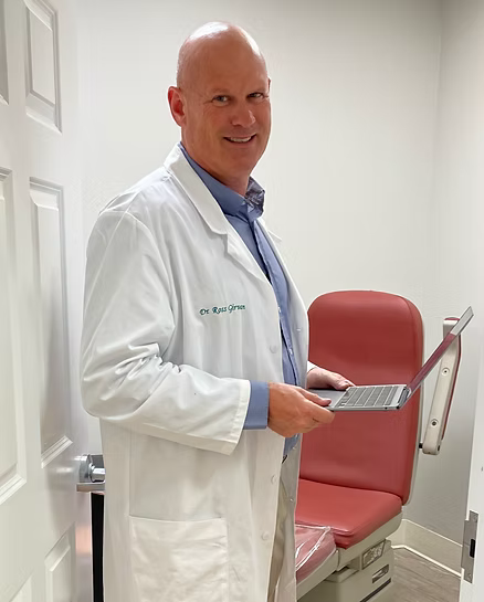 A smiling doctor in a lab coat with a stethoscope around his neck.