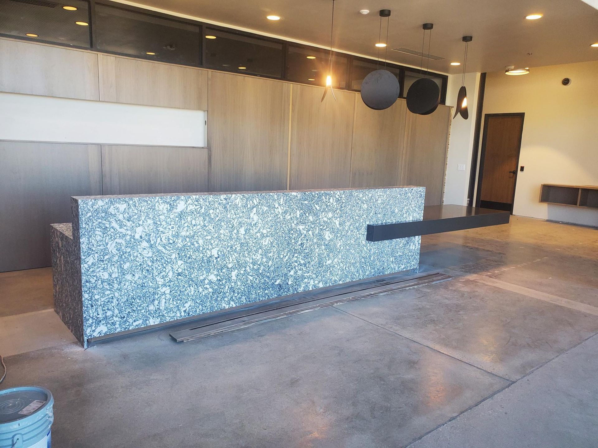 Reception desk with a speckled gray exterior. The space has concrete floors and neutral-toned walls.