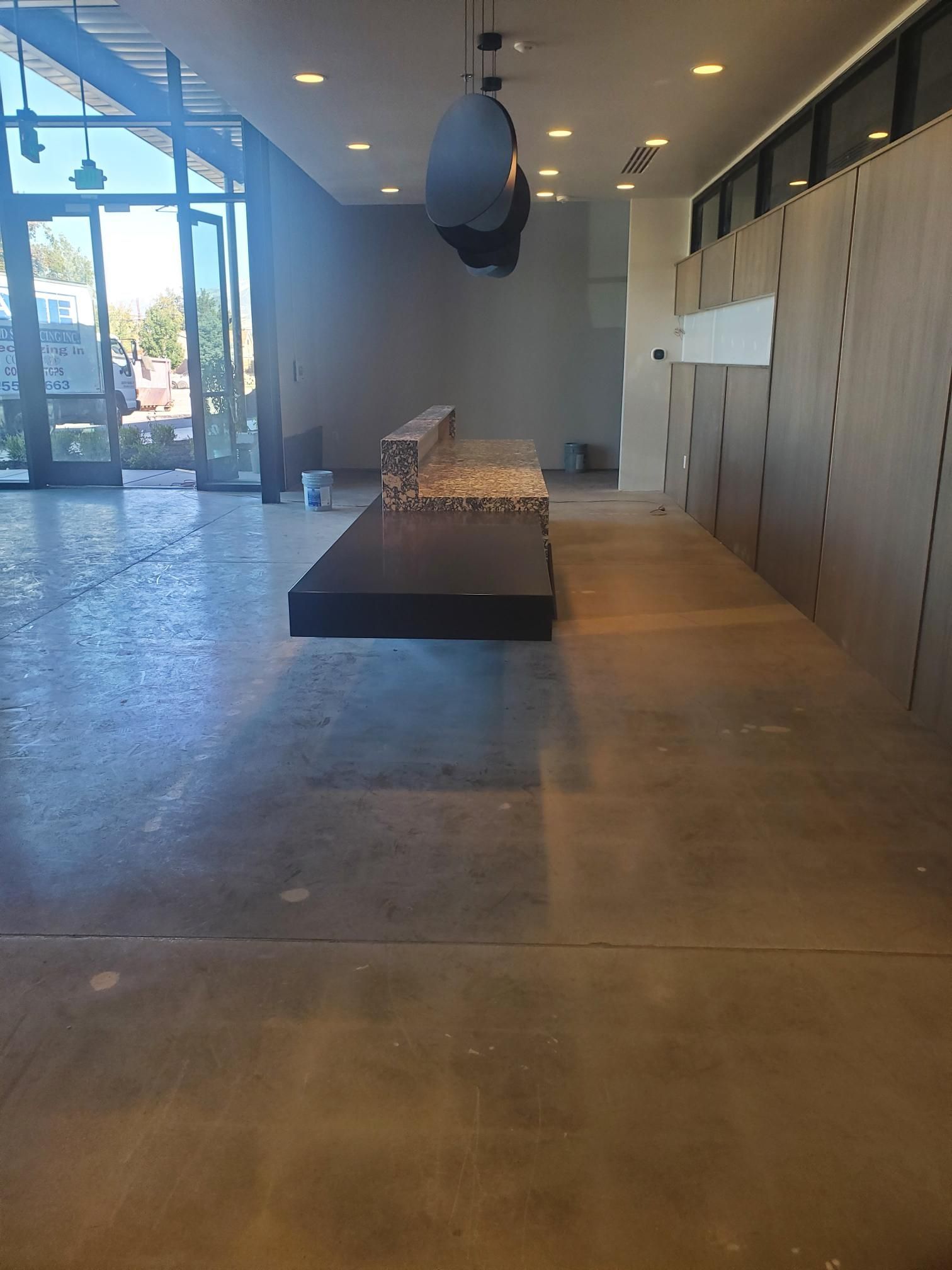 Empty store interior with exposed concrete floor, counter, and partially installed wall panels.