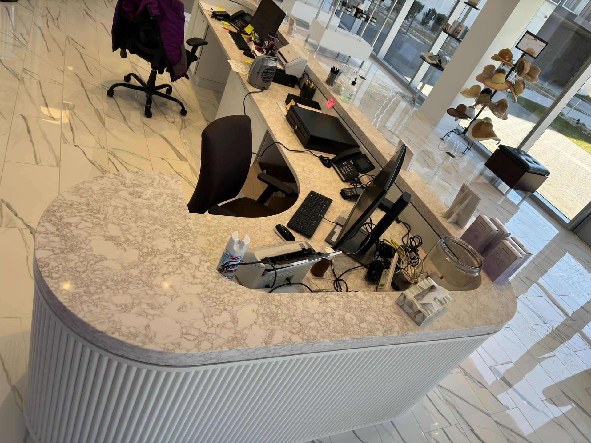 Reception desk in a bright, modern office with a marbled countertop and white fluted panels.
