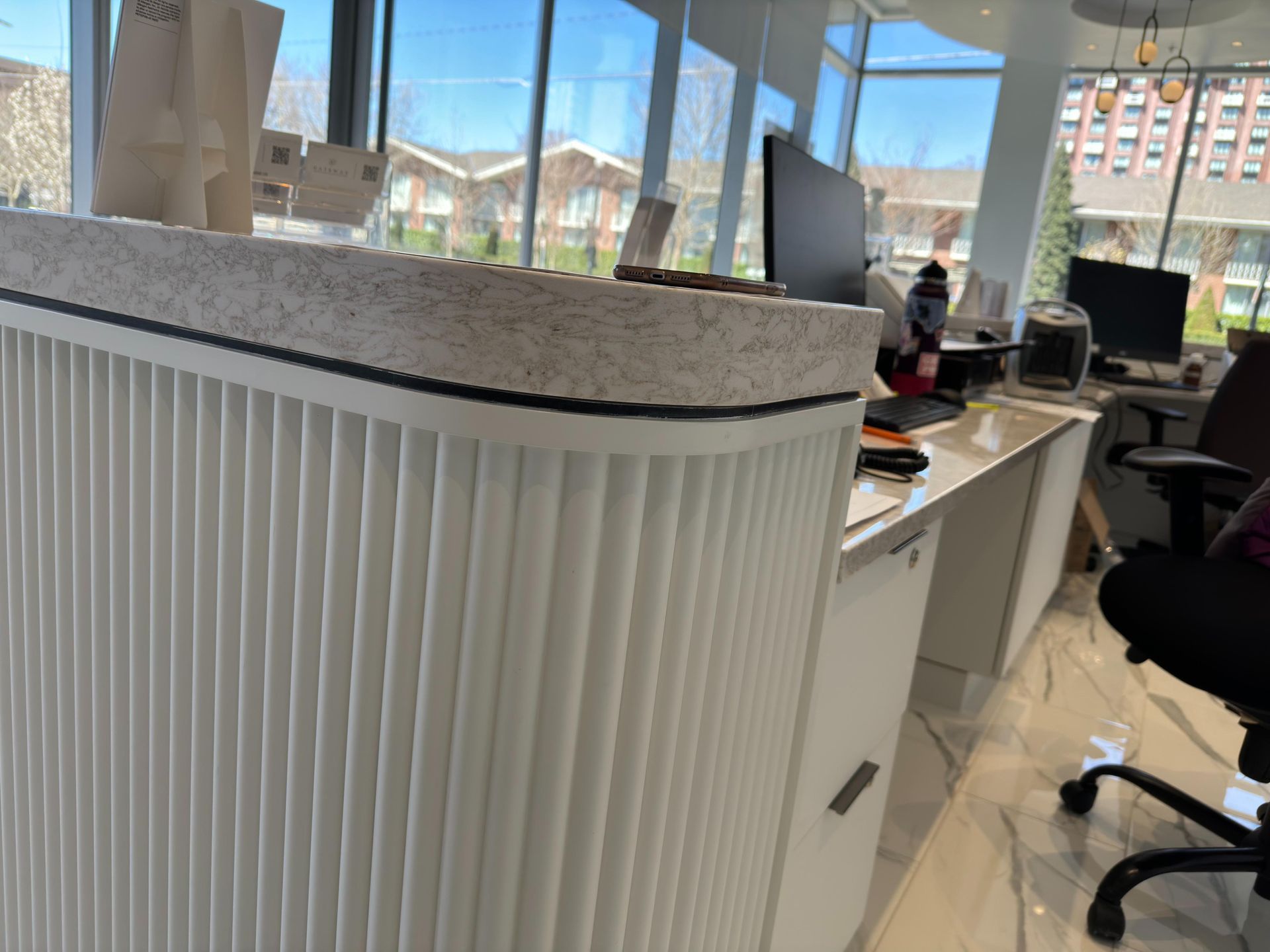 White fluted reception desk with a speckled countertop, and a computer in a modern office setting.