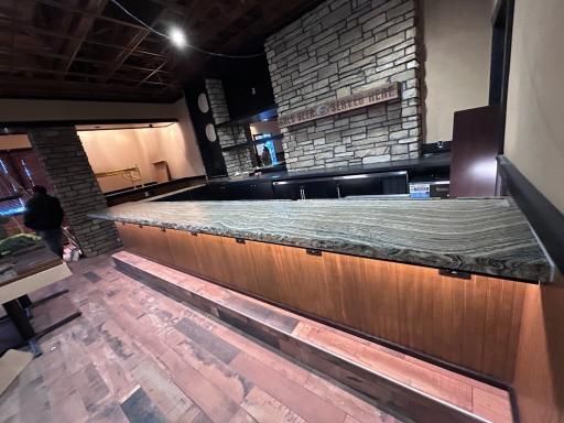 Kitchen with large island, black cabinets, white countertops, and pendant lights.