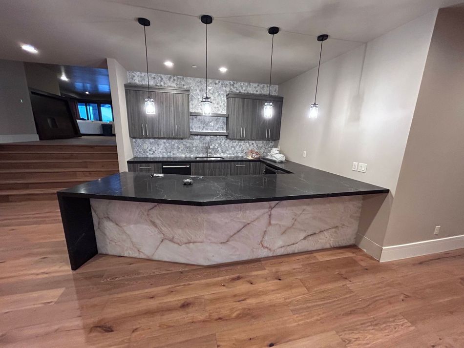 Spacious kitchen with a large island, skylight, and open mezzanine. Features light wood floors and neutral tones.