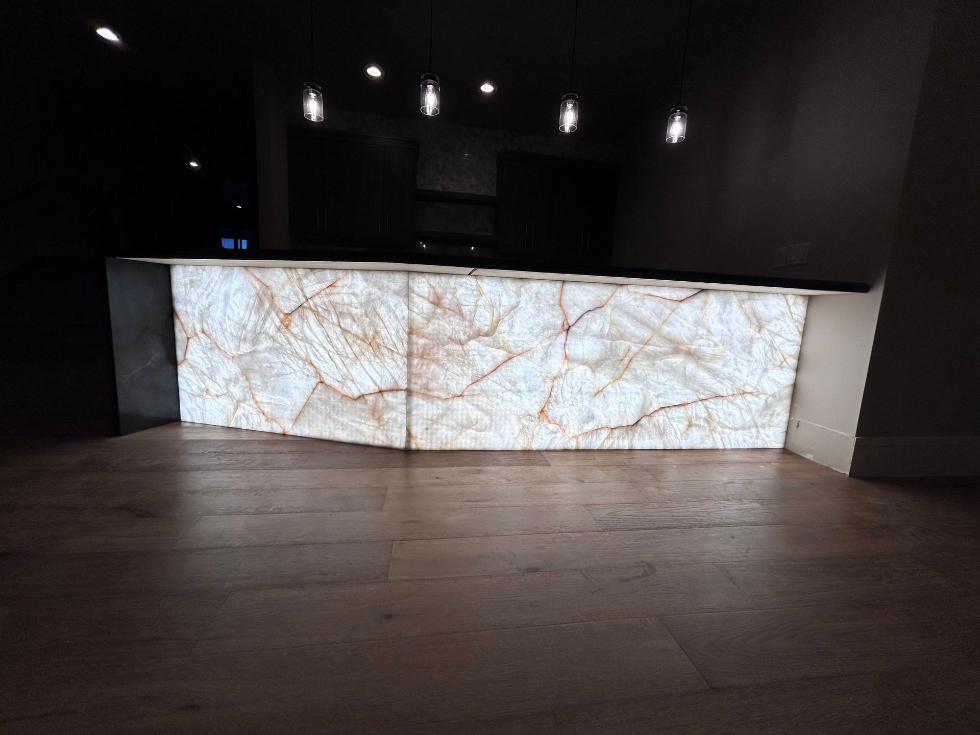 Modern office breakroom with a kitchen, bar, and seating near a large window.