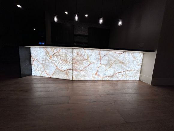 Modern office breakroom with a kitchen, bar, and seating near a large window.