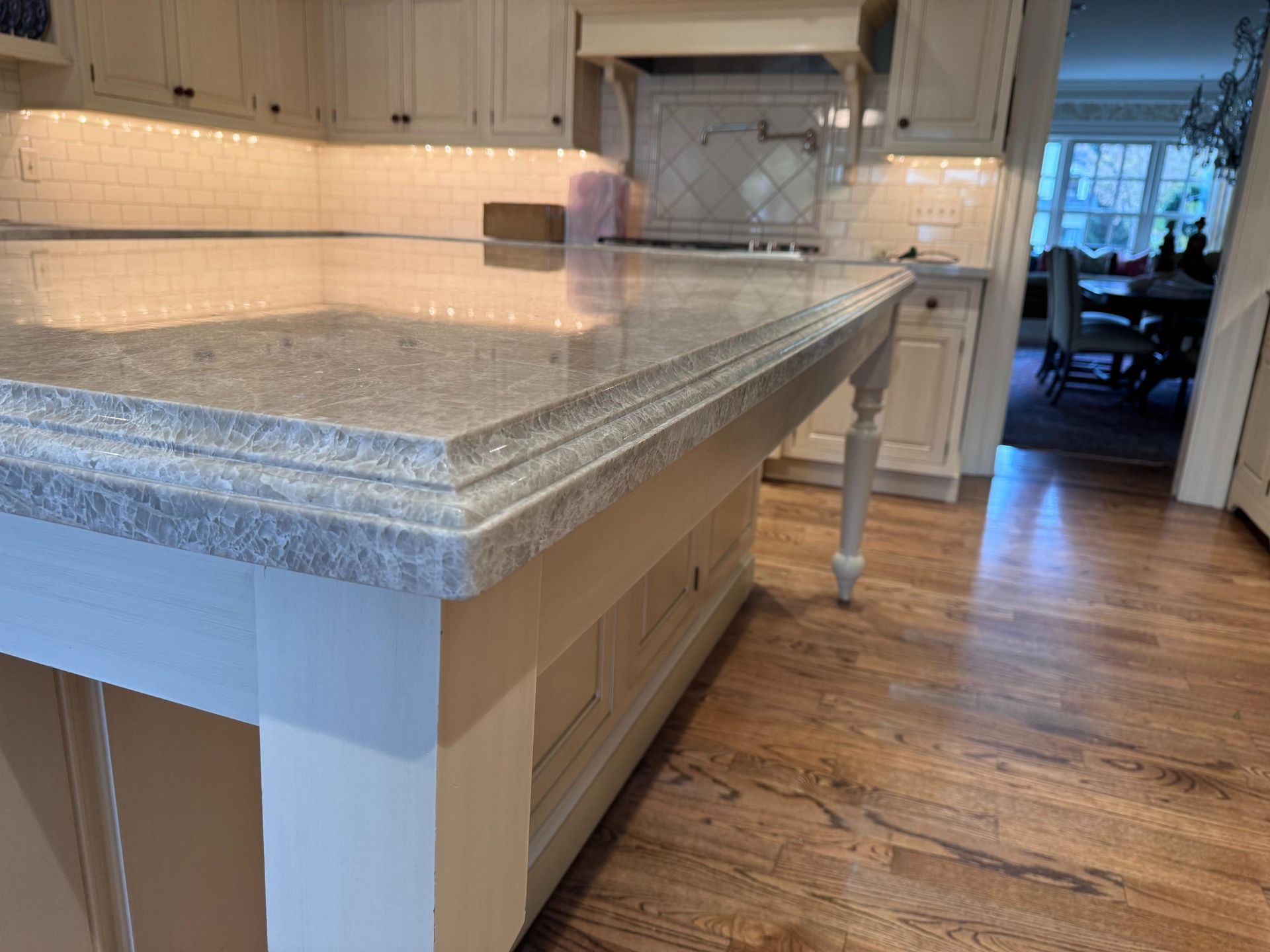 Bar with wooden cabinets, grey countertop, and mosaic backsplash.