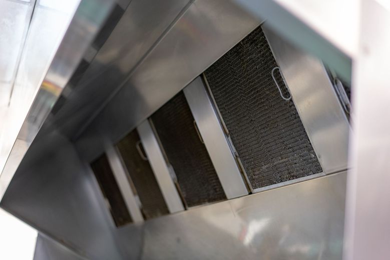 Stainless steel air vent with dark filter grilles inside a metal duct opening