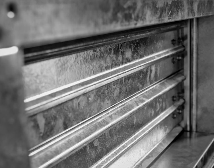 Close-up of a metal shutter with horizontal slats, seen in black and white.