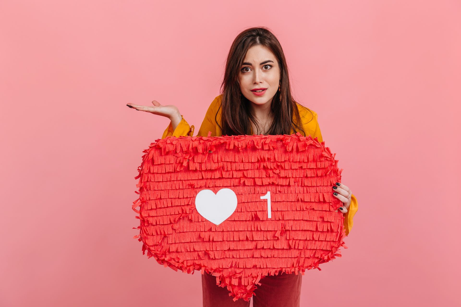 a woman is holding a red piñata with a heart on it .