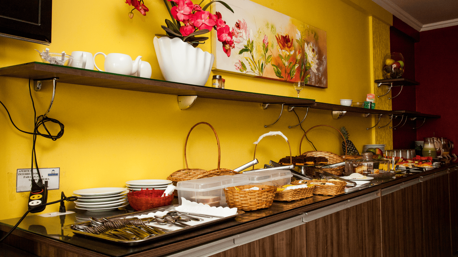 Um balcão longo com muita comida em uma sala com uma parede amarela.