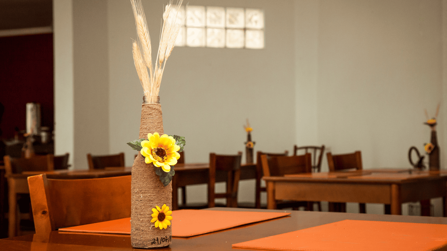 Um vaso com girassóis está sobre uma mesa em um restaurante.