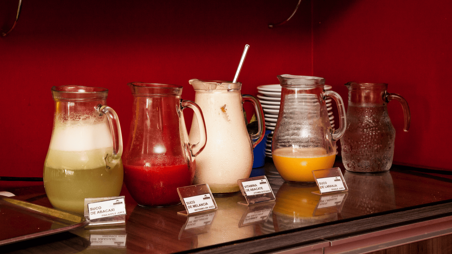 Uma fileira de jarras cheias de diferentes tipos de bebidas sobre uma mesa.