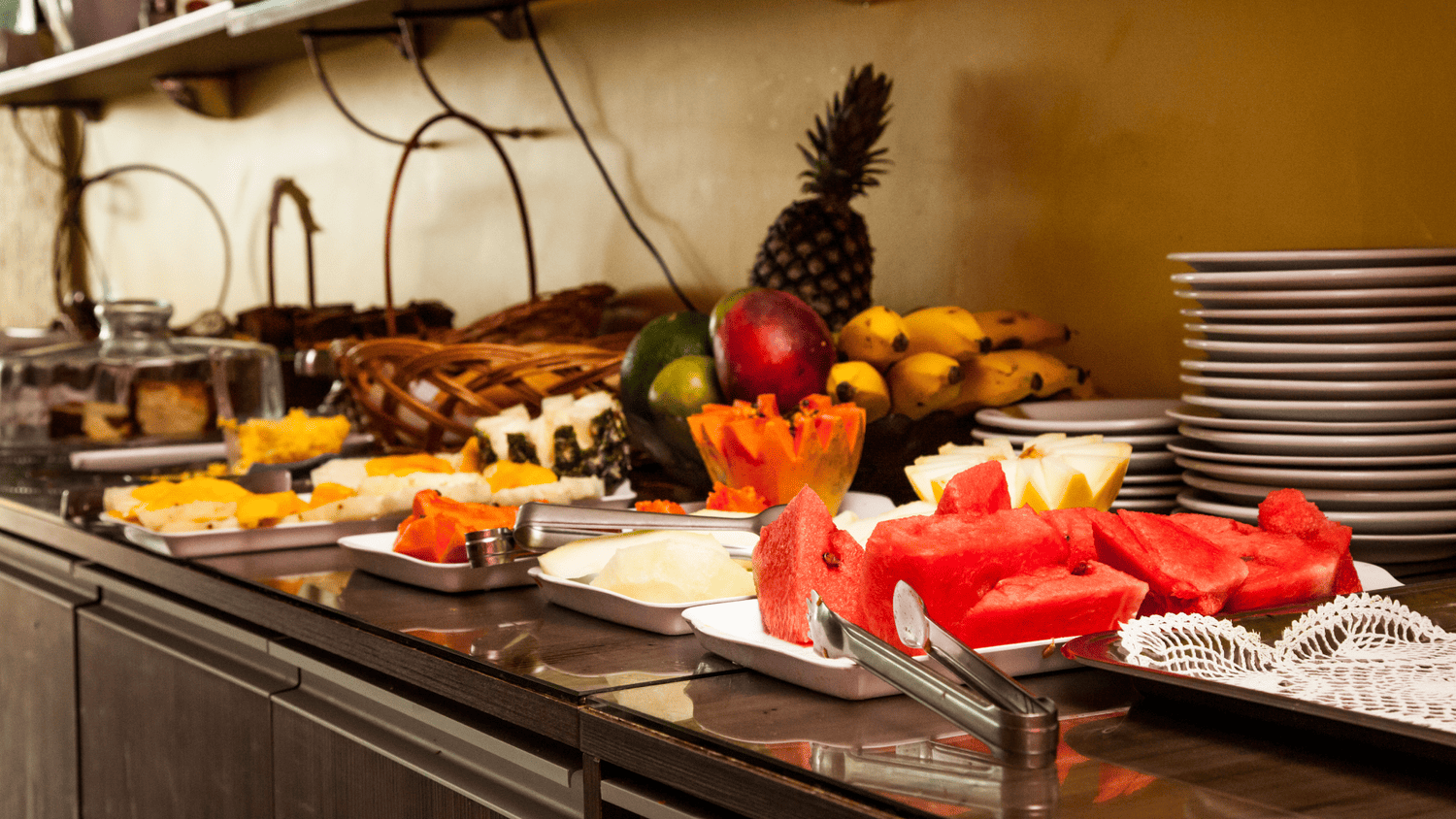 Uma mesa de bufê cheia de frutas e pratos.