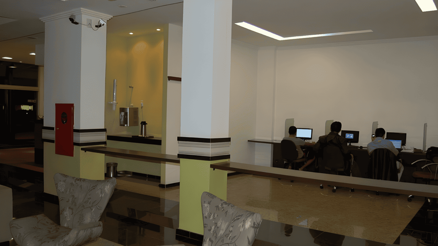 Um grupo de pessoas está sentado em mesas em uma sala com computadores.