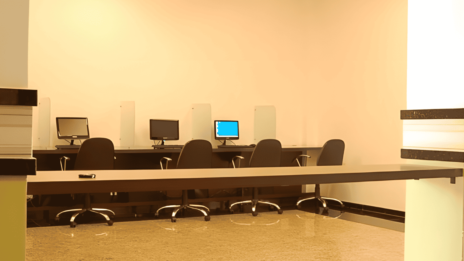 Uma fileira de mesas com monitores de computador