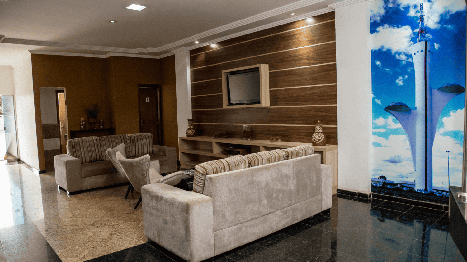 Uma sala de estar com um sofá, cadeiras e uma televisão.