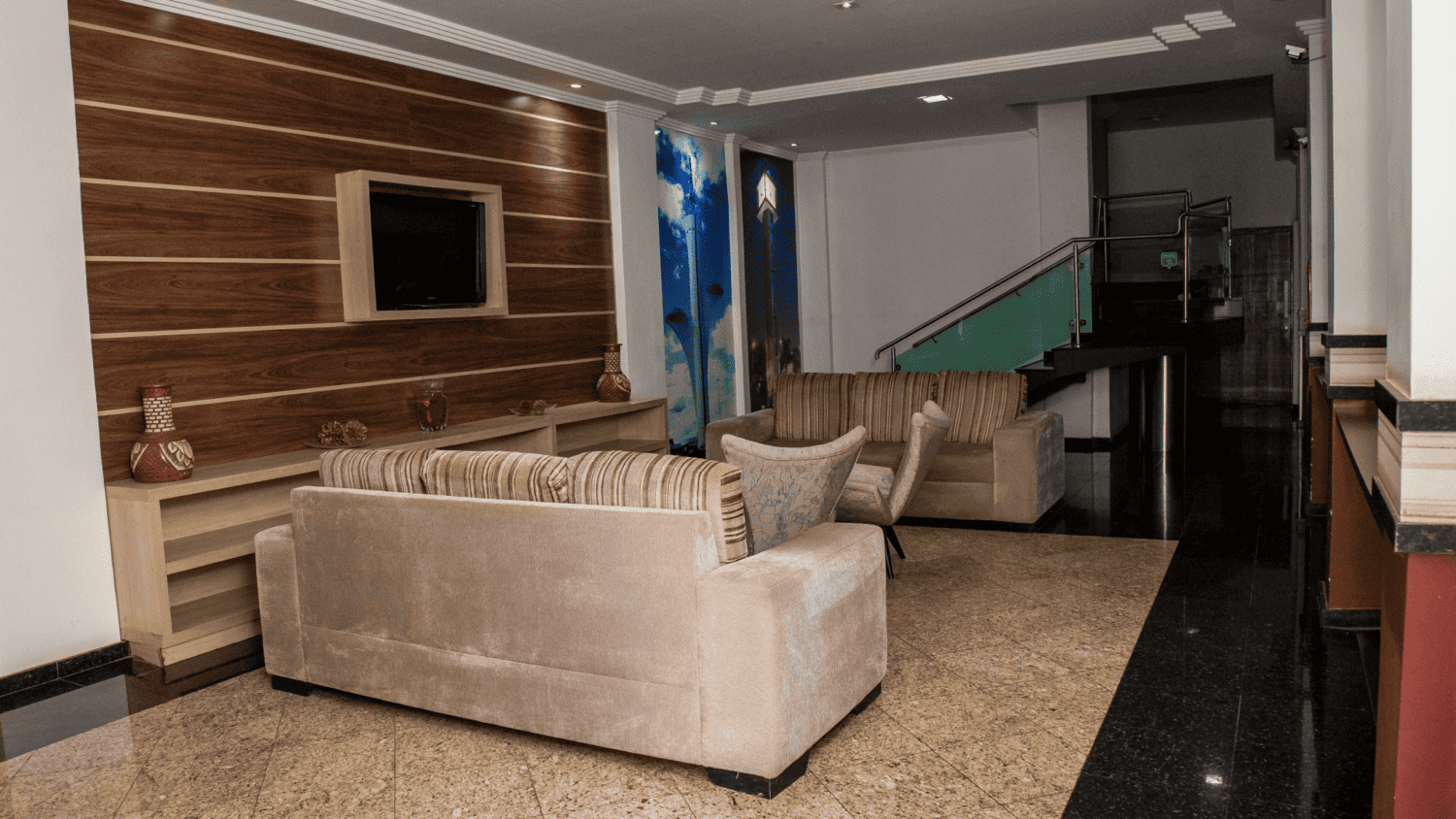 Uma sala de estar com um sofá, cadeiras e uma televisão.