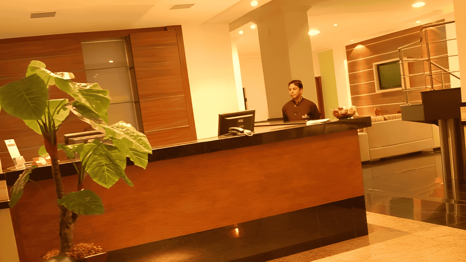 Um homem está parado atrás de um balcão no saguão de um hotel.