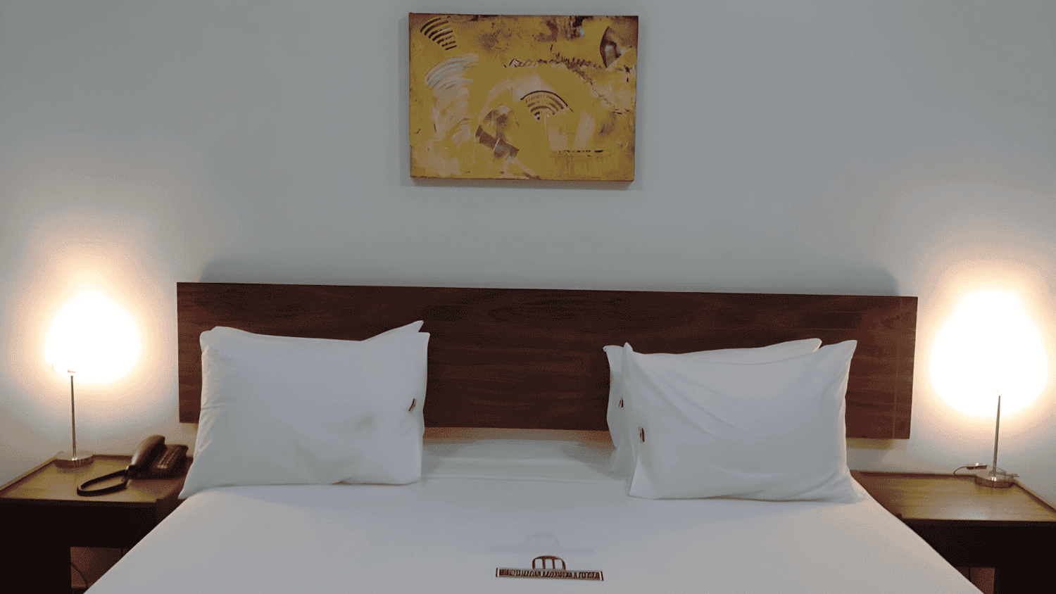 Um quarto de hotel com uma cama e uma pintura na parede