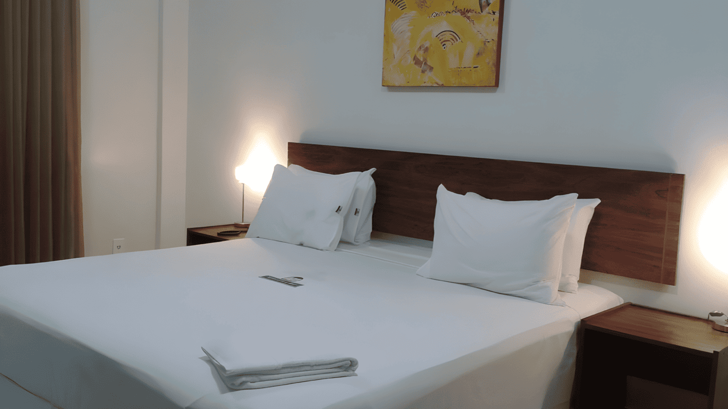 Um quarto de hotel com uma cama e uma pintura na parede